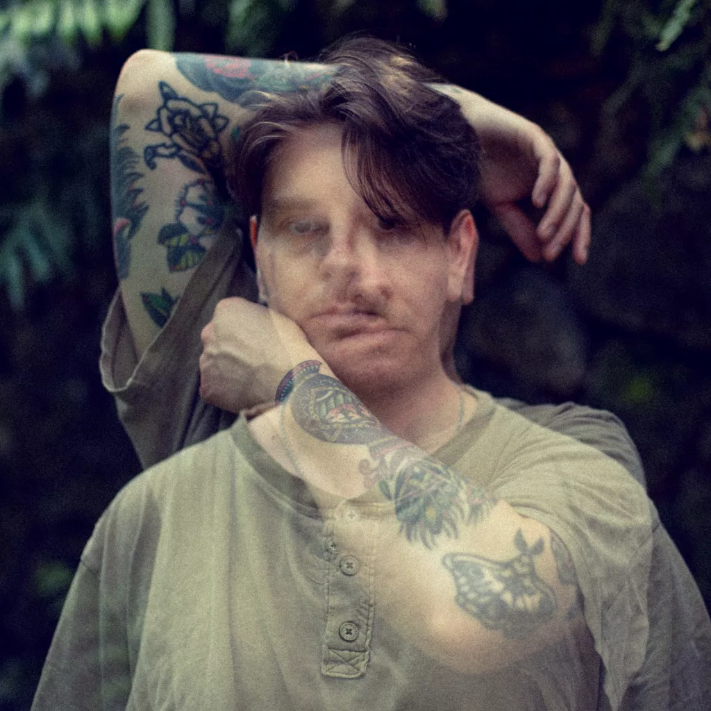 Album cover of "Shelter" by I Shiver featuring a double-exposure image of the artist with raised tattooed arms against a blurred natural background.