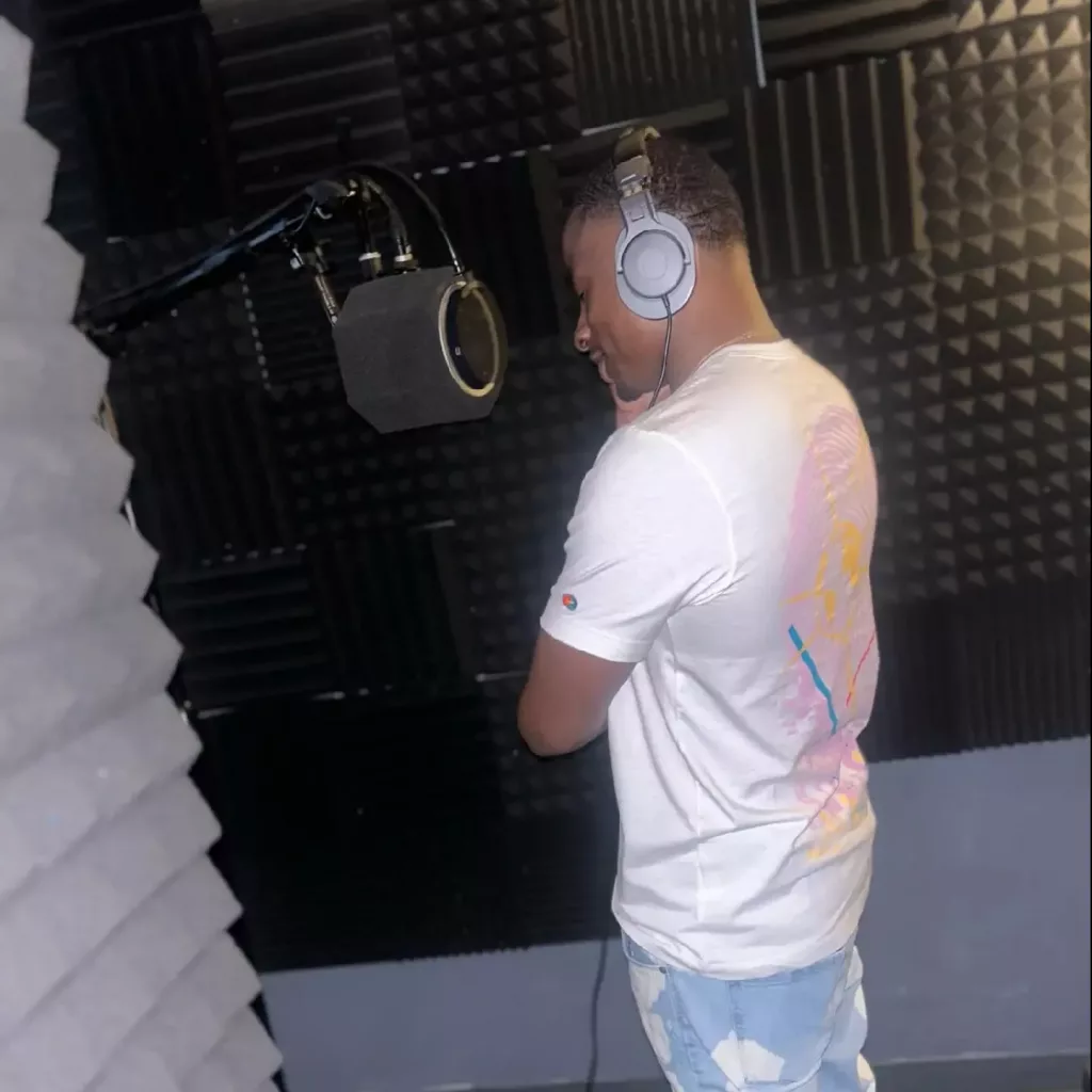 Artist recording vocals in a professional studio while wearing headphones.