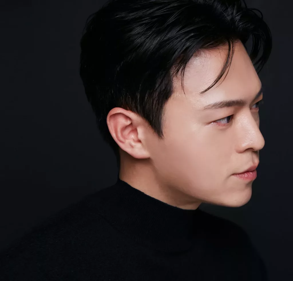 A side-profile photograph of singer-songwriter Ian Chung wearing a black turtleneck, gazing to the right against a dark background.