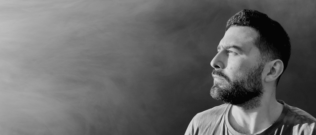 Black and white profile photo of Stereo Bit, featuring a bearded man looking intently into the distance against a smoky background.