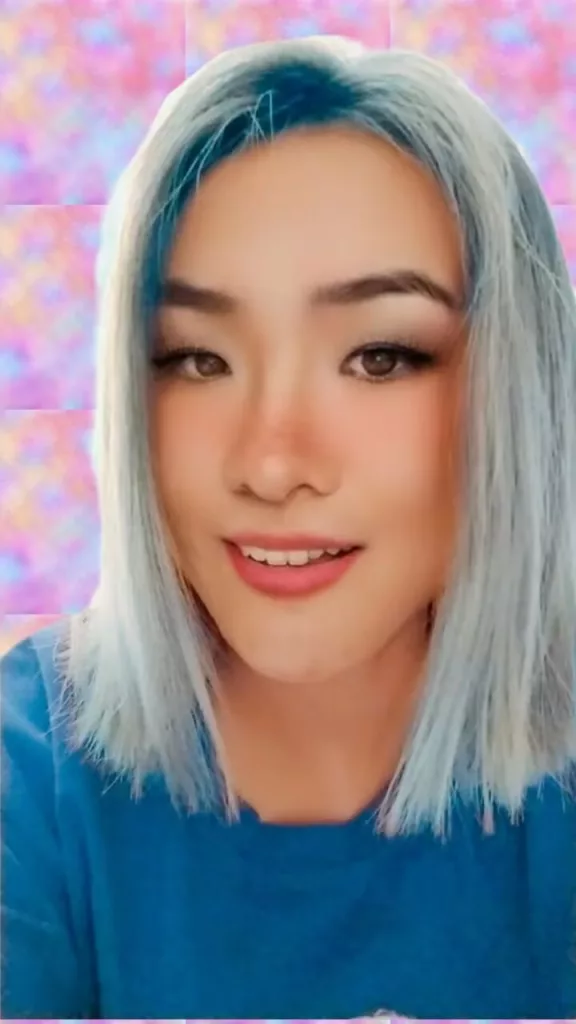 Mack Vapordream, an artist with light blue hair and a warm smile, against a pastel, dreamy background, reflecting his unique future-nostalgia music style.